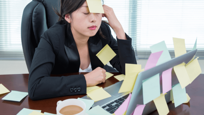 A stressed female executive sitting at desk with post it notes everywhere.