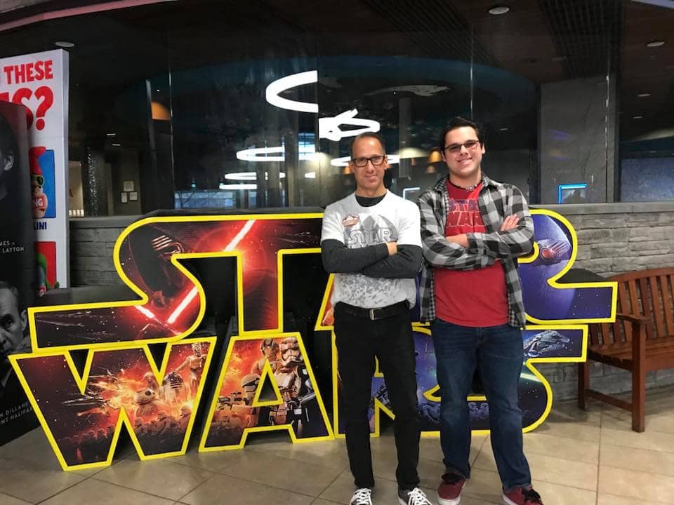 Father and Son standing in front of Star Wars sign.