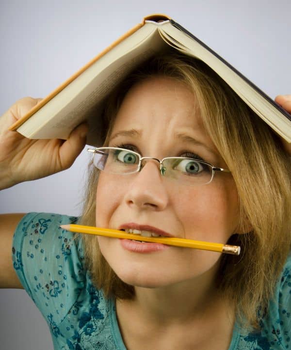 woman with book on her head and pencil in her mouth showing a frustrated student working on bcba exam prep.